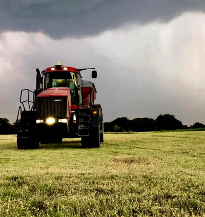 Roth Fertilizer tractor in a pasture ahead of a storm
